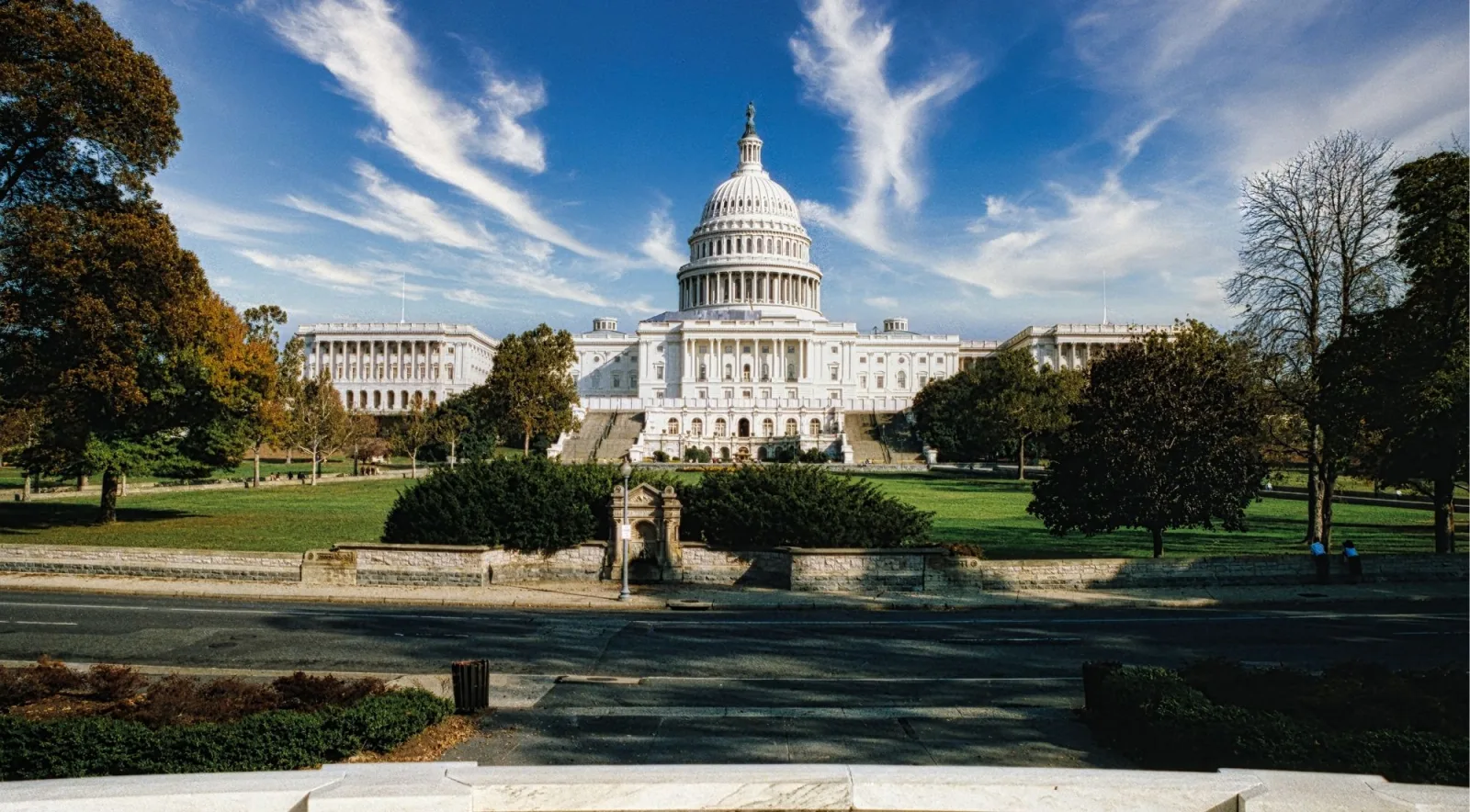 The U.S. Capitol at the far end of a wide lawn under a blue sky