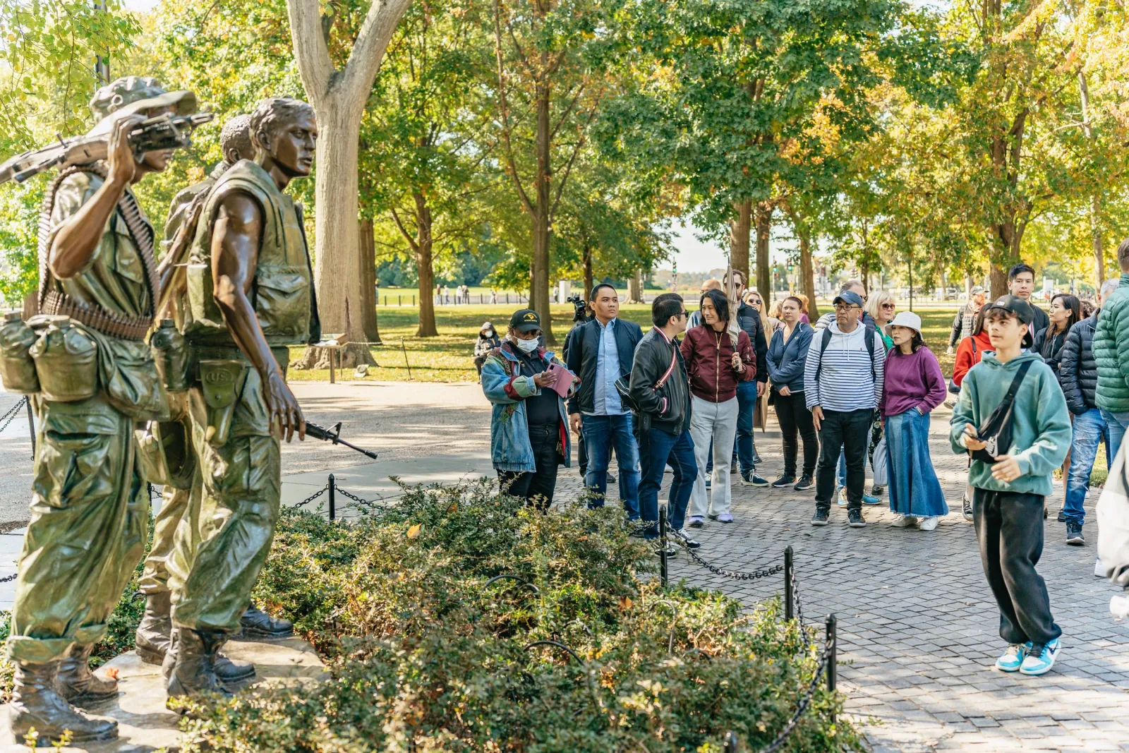 The Three Servicemen statue at the Vietnam Veterans Memorial with a tour group behind