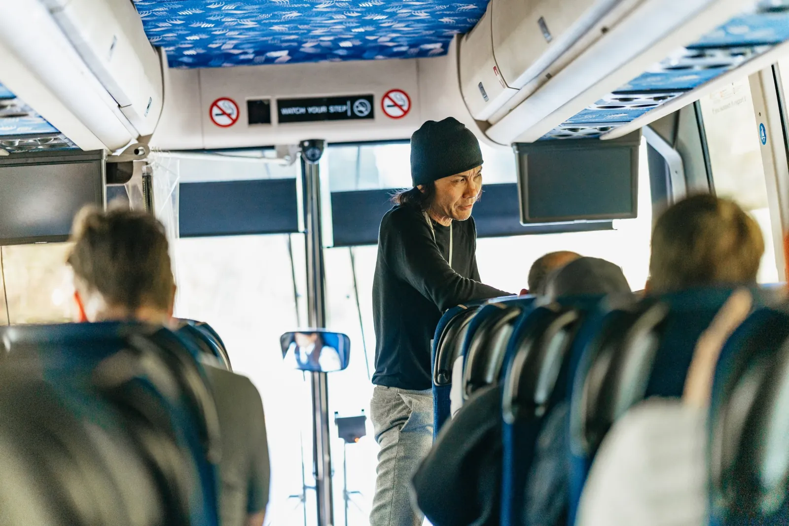 The guide speaking to passengers inside the tour coach