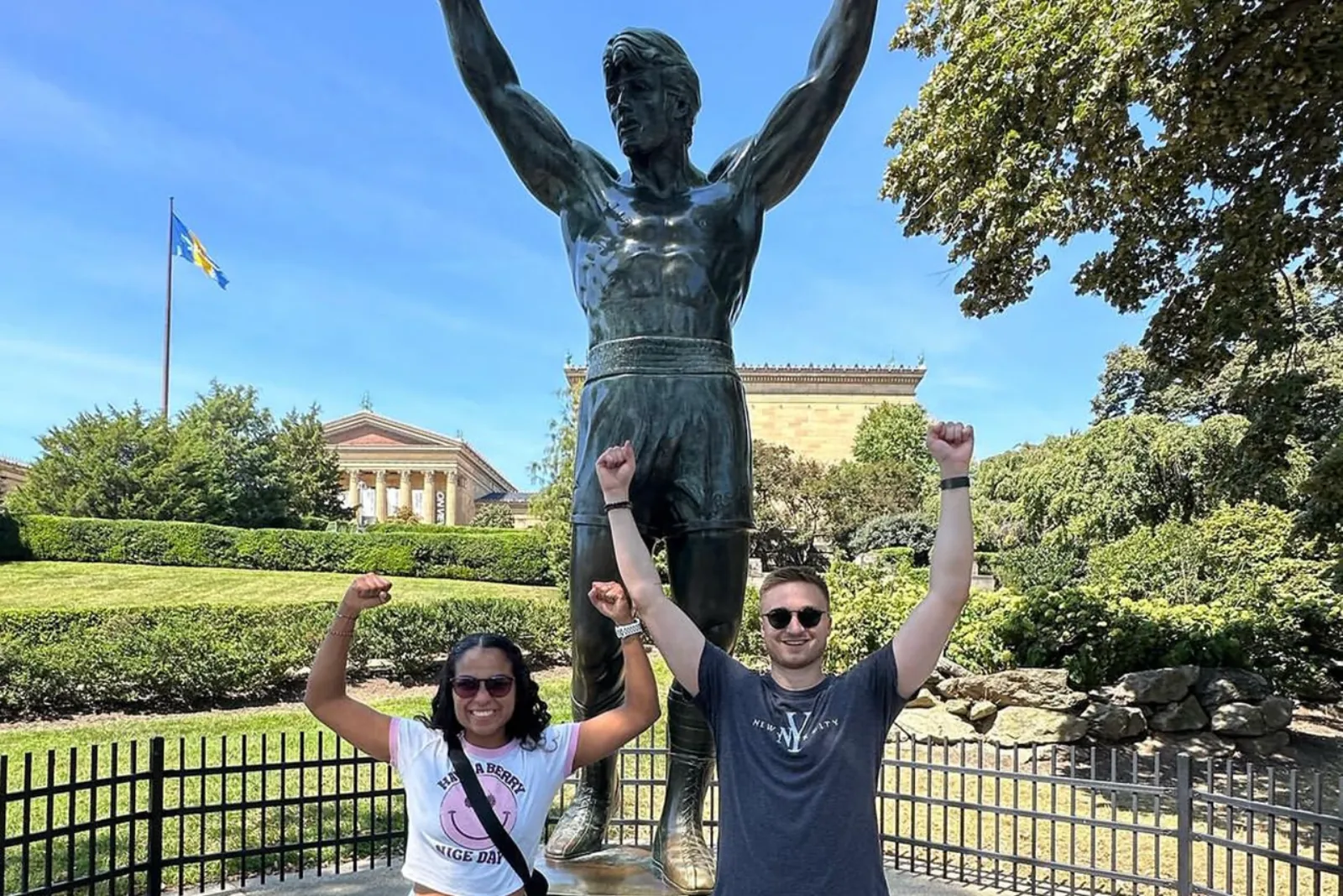 Two travellers with raised arms at the Rocky statue in Philadelphia